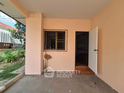 Charming entrance to a cozy home with a welcoming open door and garden view.