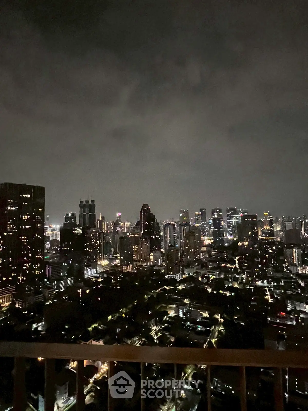 Stunning city skyline view from a high-rise balcony at night, showcasing vibrant urban lights.