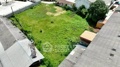 Spacious green plot surrounded by industrial buildings, ideal for development opportunities.
