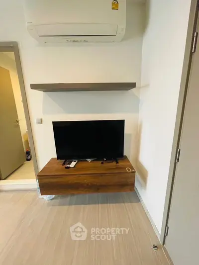 Modern living room with wall-mounted TV and air conditioning unit, featuring sleek wooden furniture.