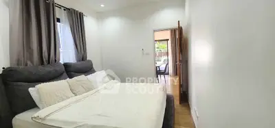Cozy bedroom with plush bedding and natural light, leading to a bright outdoor view.