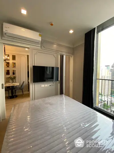 Modern bedroom with city view, featuring a wall-mounted TV and air conditioning.