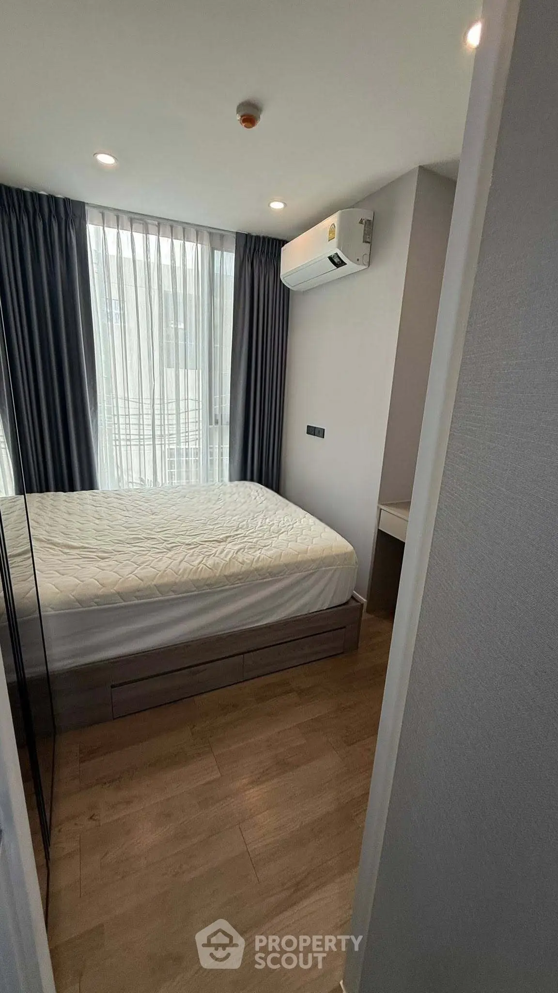 Modern bedroom with large window and air conditioning in a stylish apartment.