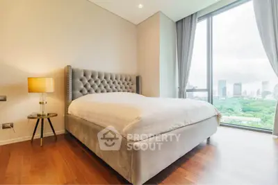 Luxurious bedroom with plush bed and stunning city view through large window.