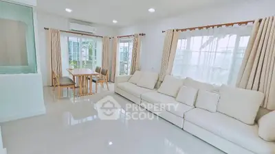 Spacious living room with modern white sofa and dining area, flooded with natural light.