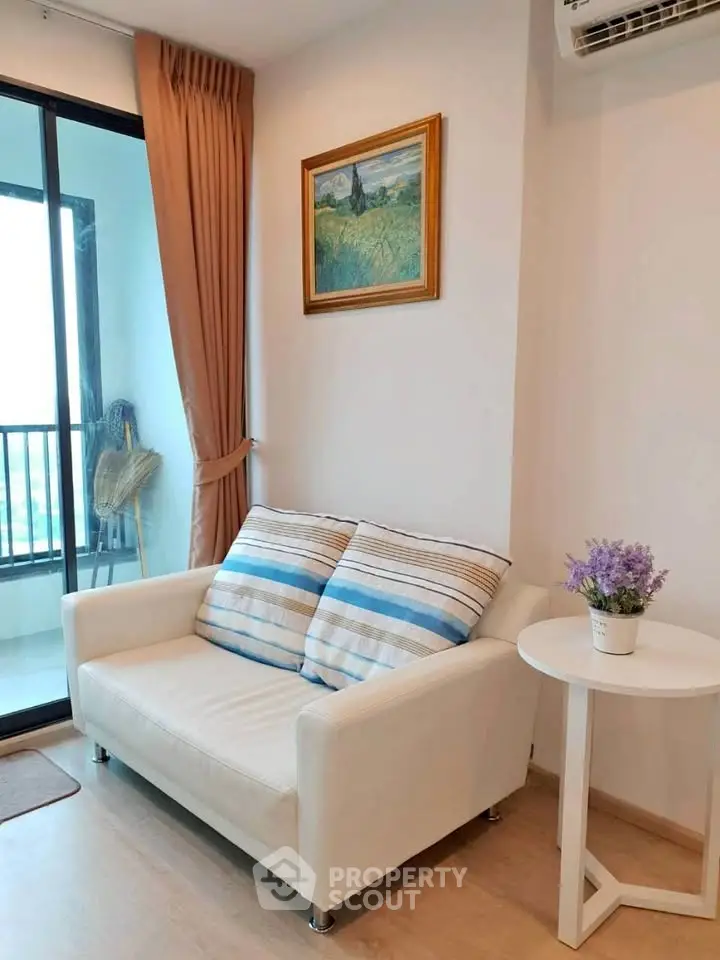 Cozy living room with white sofa, striped cushions, and balcony view in modern apartment.