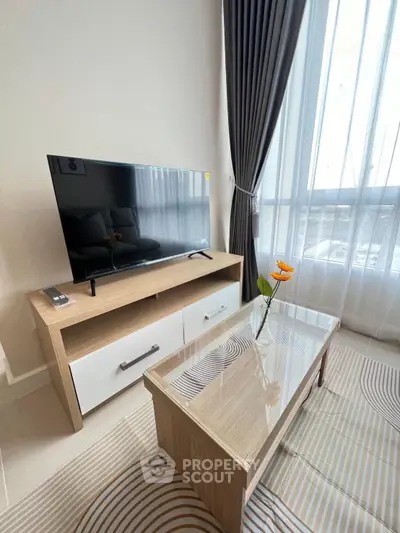Modern living room with stylish TV stand and elegant coffee table near large window with curtains.