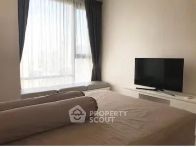 Modern bedroom with large window and TV, featuring elegant curtains and a cozy bed setup.