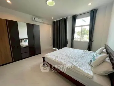 Spacious bedroom with modern furnishings and large window offering natural light.