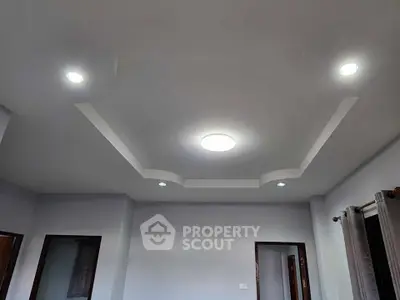 Modern living room with stylish ceiling lights and neutral walls.