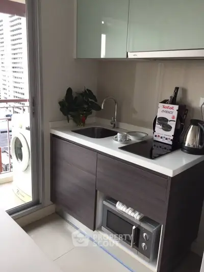 Modern compact kitchen with balcony view, featuring sleek cabinetry and appliances.