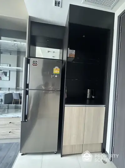 Modern kitchen corner with sleek fridge and stylish cabinetry in contemporary apartment.