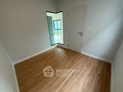 Spacious empty room with wooden flooring and modern door, ideal for customization.