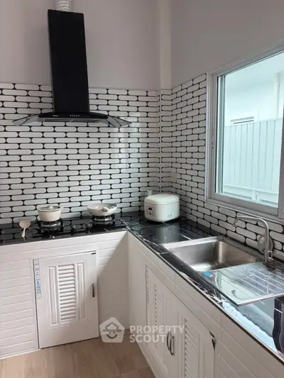 Modern kitchen with sleek black and white design, featuring gas stove and ample counter space.