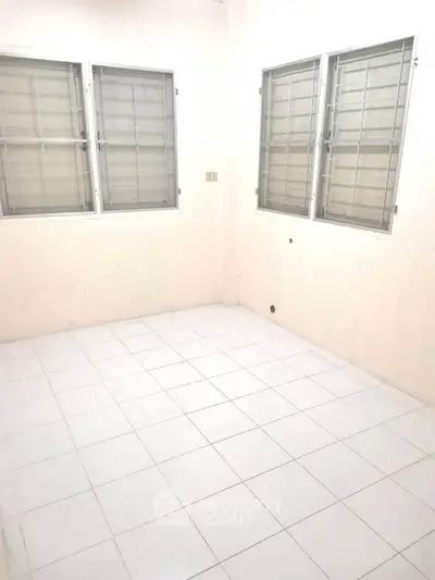 Bright empty room with tiled floor and large windows, perfect for customization.