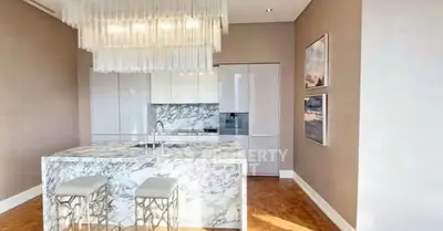 Luxurious modern kitchen with marble island and elegant lighting in upscale apartment.