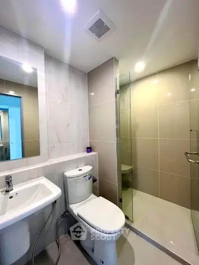 Modern bathroom with sleek design, featuring a glass shower enclosure and elegant fixtures.