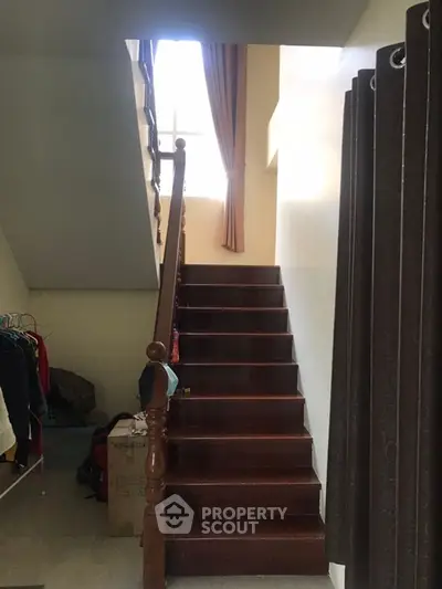 Cozy staircase with natural light and elegant wooden railing in a charming home.
