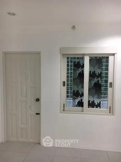 Minimalist interior with white door and window featuring cityscape design