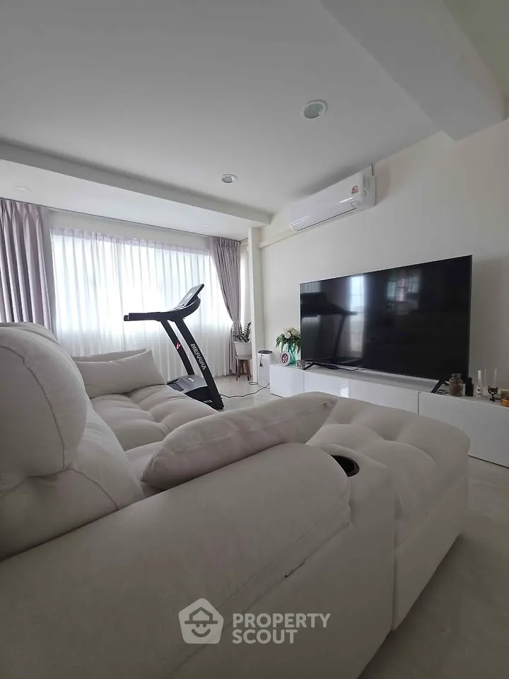 Spacious living room with modern decor, large TV, and exercise equipment, perfect for relaxation and fitness.