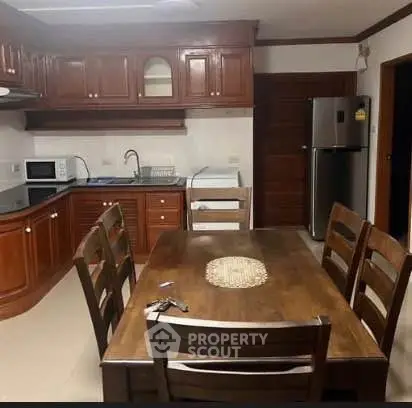 Spacious kitchen with wooden cabinets and dining table, featuring modern appliances.