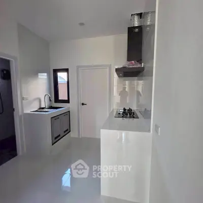 Modern kitchen with sleek white cabinetry and built-in gas stove, featuring a minimalist design and ample natural light.
