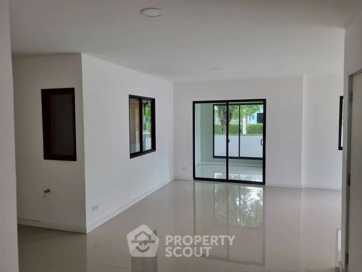 Spacious modern living room with large windows and glossy tile flooring.