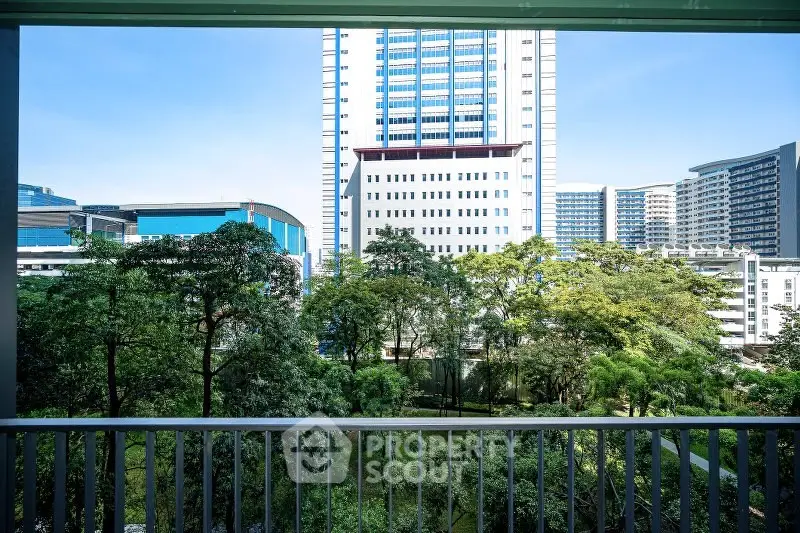 Stunning urban view from a balcony overlooking lush greenery and modern high-rise buildings.