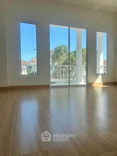 Spacious room with large windows and balcony access, offering abundant natural light and serene views.