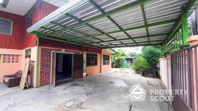 Spacious covered parking area in a charming residential property with lush greenery.