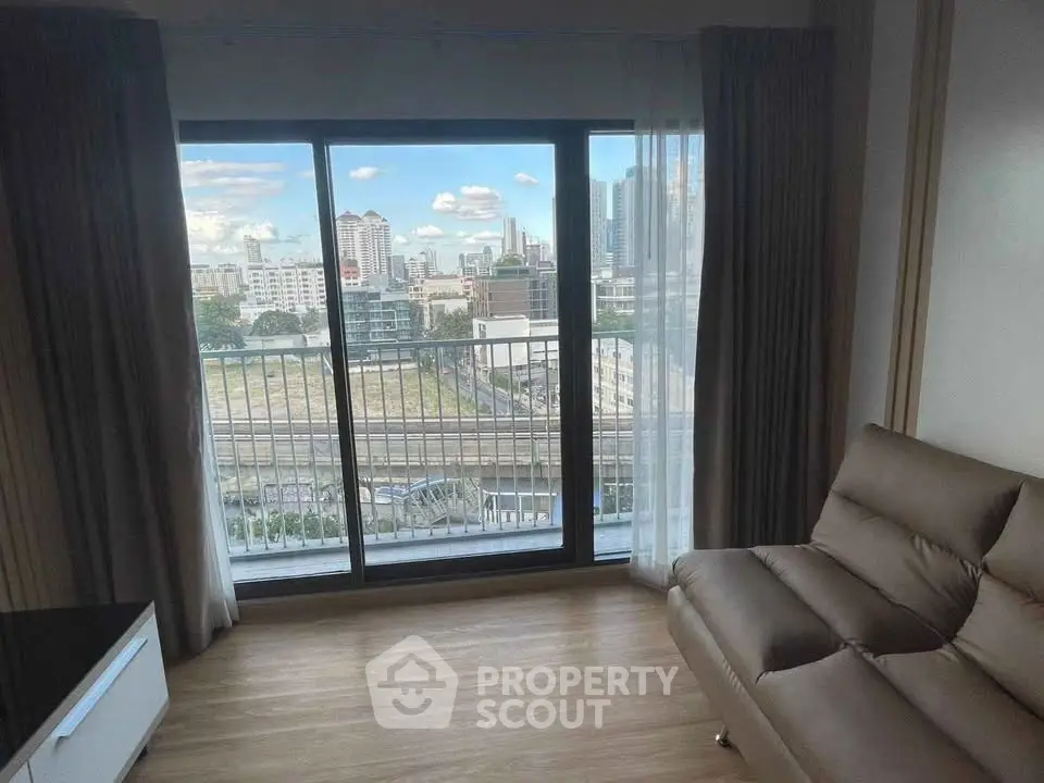 Modern living room with large window offering stunning city view and cozy seating area.