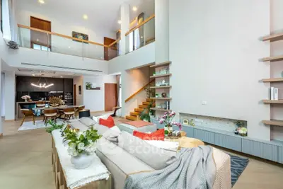 Spacious modern living room with high ceilings and elegant decor, featuring an open layout and stylish furnishings.
