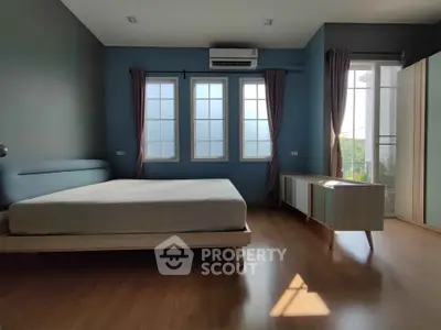 Spacious bedroom with large windows and modern furniture, featuring a serene ambiance and natural light.