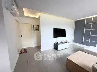 Modern living room with sleek design and wall-mounted TV in a bright apartment.