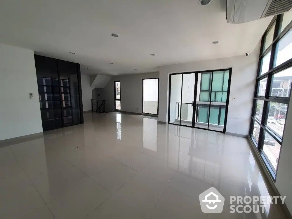 Expansive and sunlit living room with gleaming tiled floors, large windows offering ample natural light, and a versatile open layout perfect for customization.