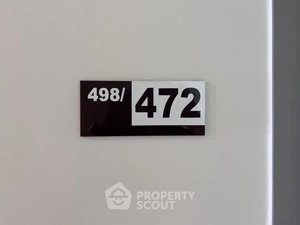 Apartment number sign on a white wall indicating unit 498/472, perfect for real estate listings.
