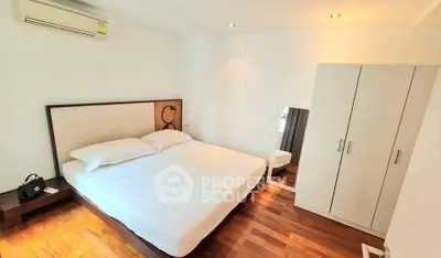 Spacious bedroom with wooden flooring and modern furnishings in a stylish apartment.