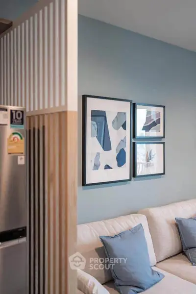 Modern living room with stylish decor and cozy seating area, featuring abstract art and soft blue accents.
