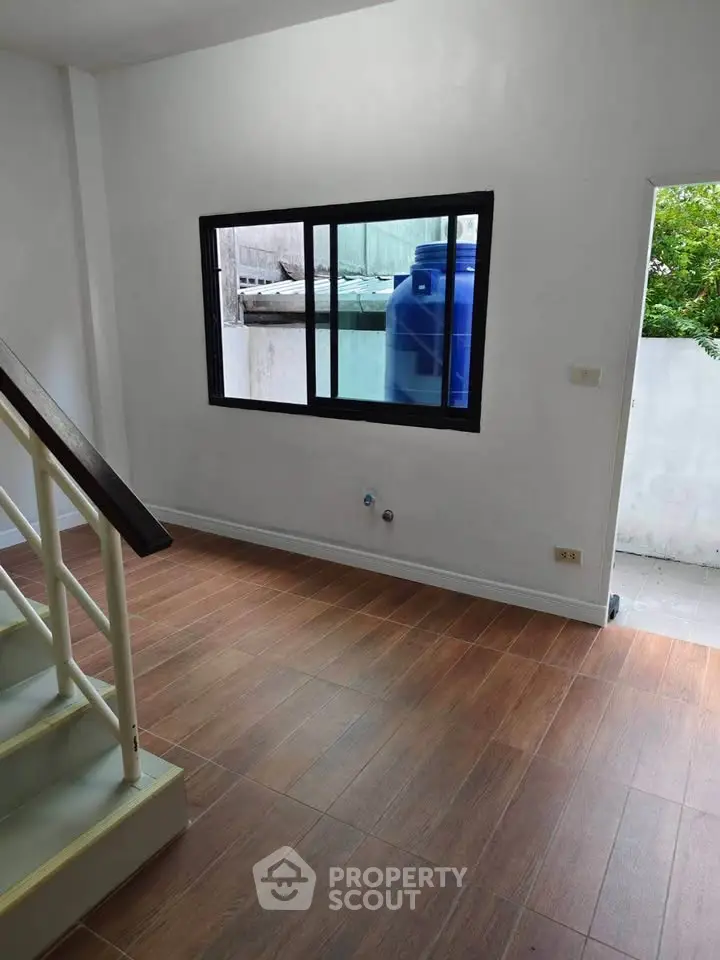Spacious interior with wooden flooring and large window, perfect for natural light.