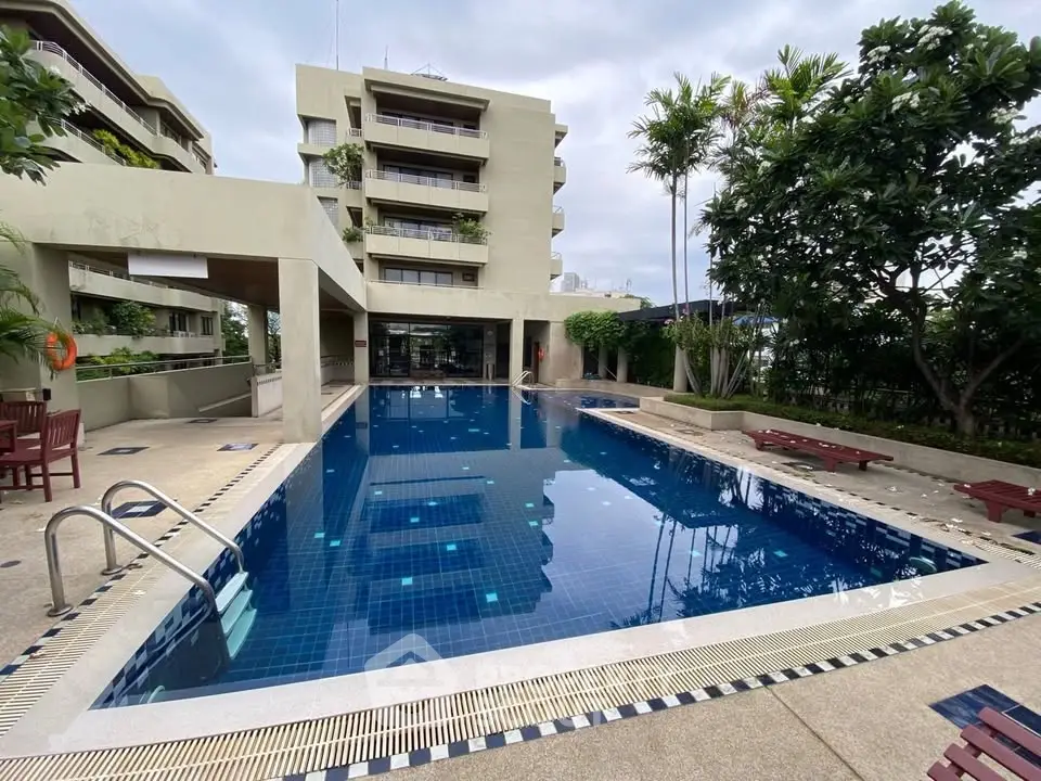 Luxurious residential building with a pristine outdoor pool and lush greenery.