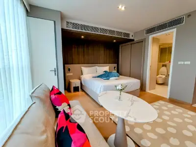 Modern bedroom with cozy seating area and ensuite bathroom in luxury apartment.