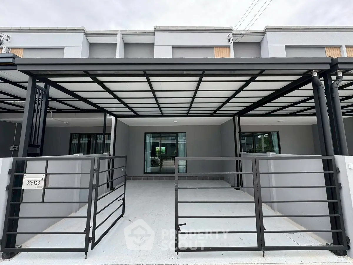 Modern townhouse exterior with sleek metal gate and covered parking area.