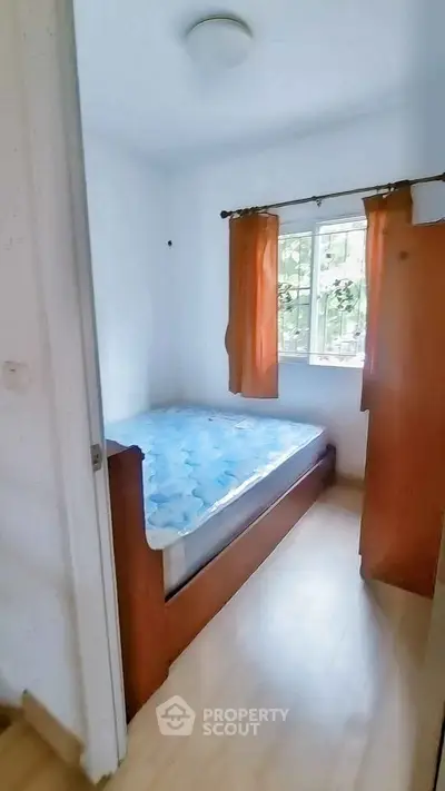 Cozy small bedroom with natural light and wooden furniture