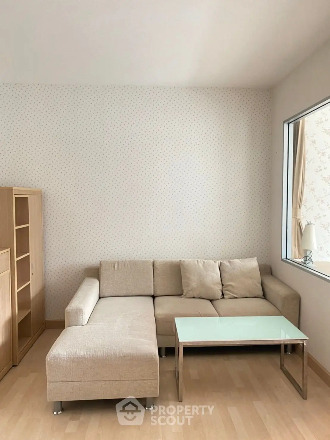 Cozy living room with beige sectional sofa and glass coffee table, perfect for relaxation.