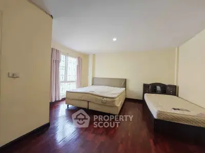Spacious bedroom with two beds and wooden flooring in a well-lit room.