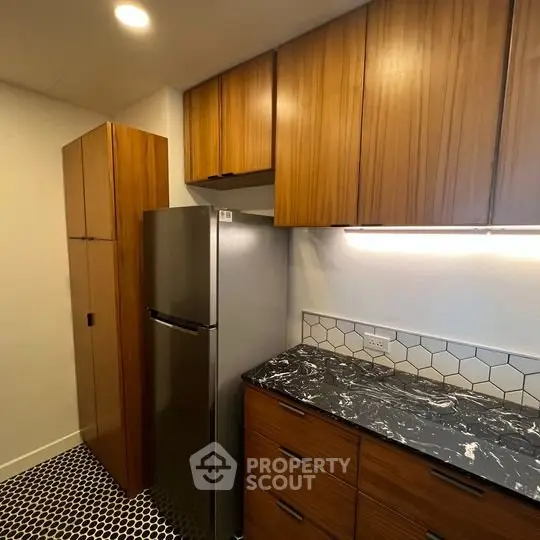 Modern kitchen with sleek wooden cabinets and stylish black marble countertop.