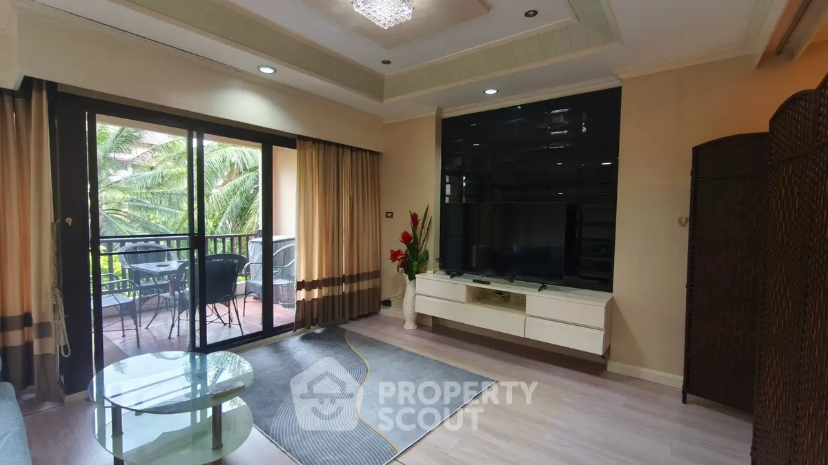 Spacious living room with balcony access and modern decor in a tropical setting.