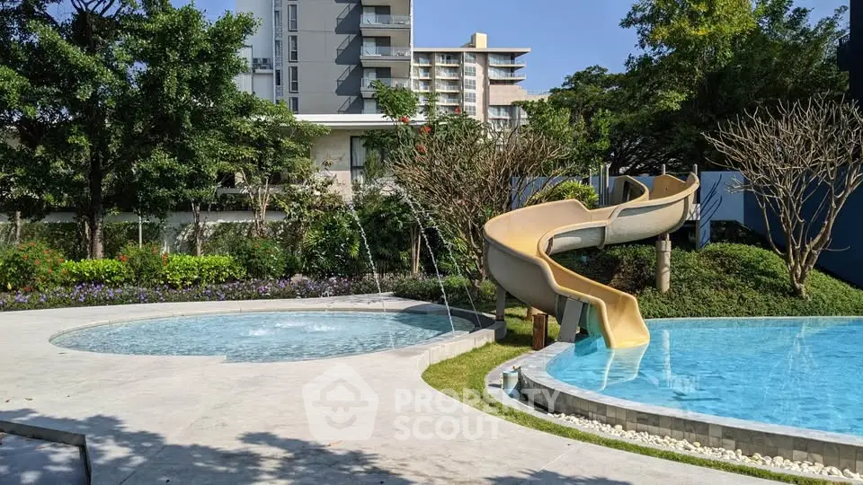 Luxurious outdoor pool area with slide in modern residential complex