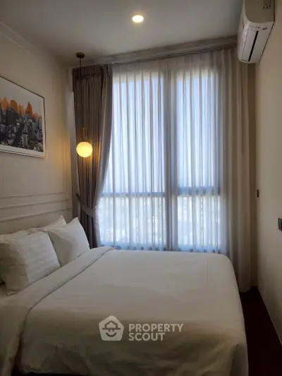 Cozy bedroom with large window and elegant decor, perfect for relaxation.
