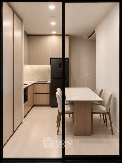 Modern kitchen with sleek cabinetry and dining area in a contemporary apartment.